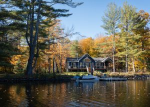 Beautiful autumn scene of a riverside cottage on the Muskoka River surrounded by a vibrant forest